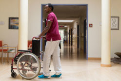 Estifanos Besrat schiebt Rollstuhl durch Krankenhausflur.
